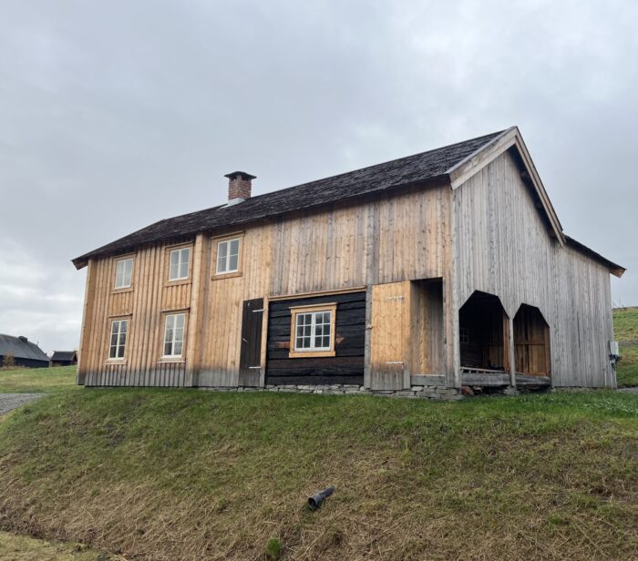 Lafte hus kledd med ny stående bordkledning og tak av stikkespon. Småbruket Rye ferdig istandsatt etter flytting. Uthusdelen og låven er nybygd.