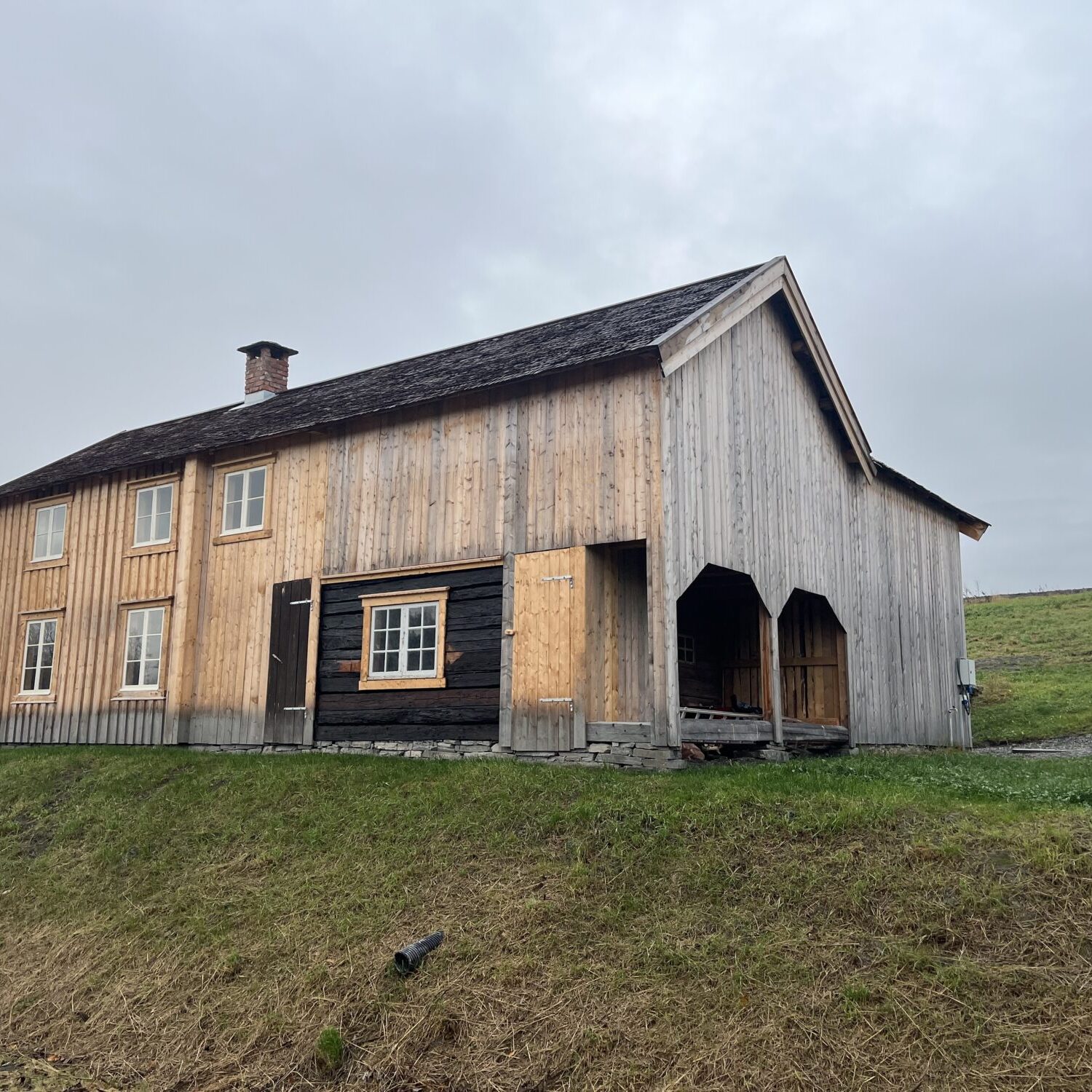 Lafte hus kledd med ny stående bordkledning og tak av stikkespon. Småbruket Rye ferdig istandsatt etter flytting. Uthusdelen og låven er nybygd.